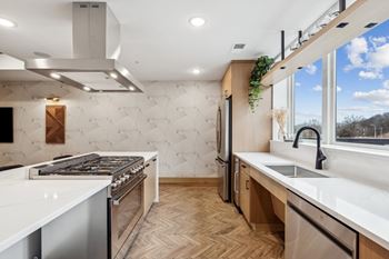 A modern kitchen with a white countertop and wooden flooring.